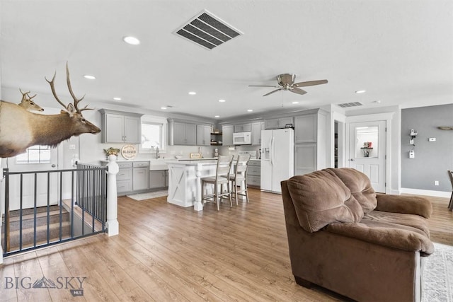 living room with ceiling fan, sink, and light hardwood / wood-style flooring