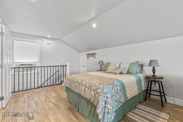 bedroom featuring hardwood / wood-style flooring, vaulted ceiling, and cooling unit