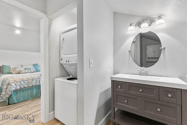 bathroom featuring stacked washing maching and dryer, wood-type flooring, and vanity