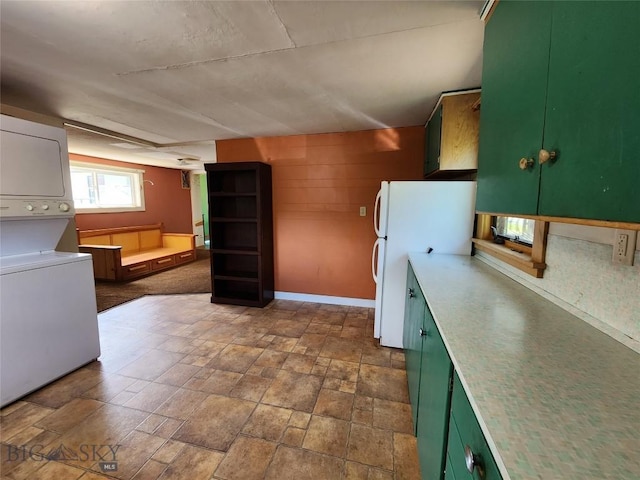 kitchen with white fridge, green cabinets, and stacked washer and clothes dryer