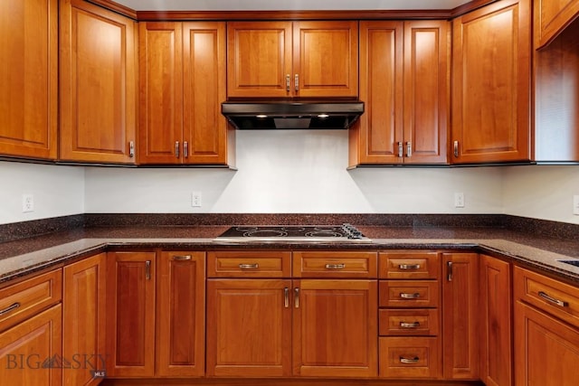 kitchen with range hood, black electric stovetop, and dark stone countertops