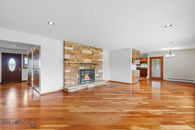 unfurnished living room featuring a notable chandelier, a stone fireplace, a baseboard radiator, and light hardwood / wood-style flooring