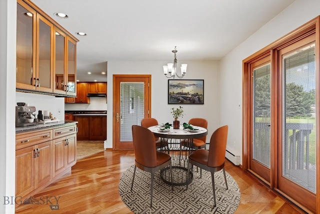 dining area with light hardwood / wood-style floors, a baseboard radiator, and an inviting chandelier