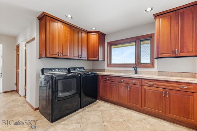 laundry room featuring light tile patterned floors, cabinets, washer and dryer, and sink