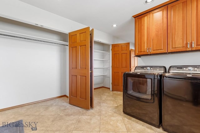 clothes washing area with washer and clothes dryer, light tile patterned flooring, and cabinets