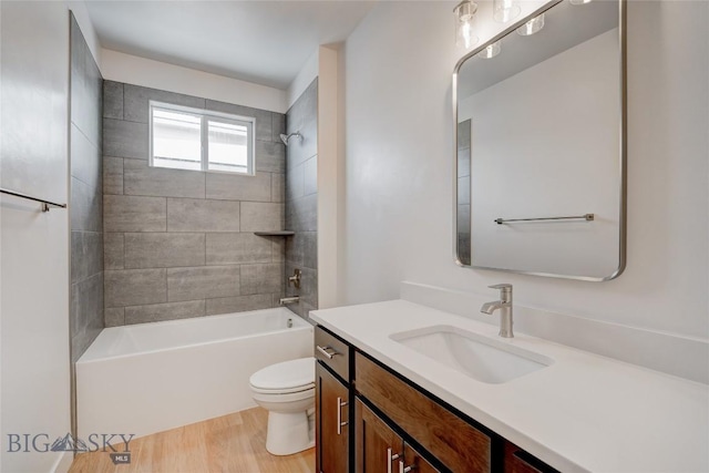 full bathroom with toilet, tiled shower / bath combo, wood-type flooring, and vanity