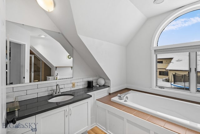 9 Park Plaza Rd, Bozeman, MT 59715 - full bathroom featuring vanity, backsplash, vaulted ceiling, and a bath