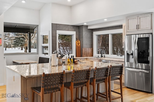 9 Park Plaza Rd, Bozeman, MT 59715 - kitchen featuring appliances with stainless steel finishes, light wood-style flooring, light stone countertops, a kitchen breakfast bar, and a sink