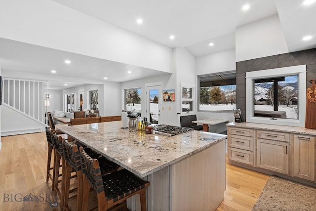 kitchen featuring a breakfast bar, light stone counters, a center island, light brown cabinets, and light hardwood / wood-style floors