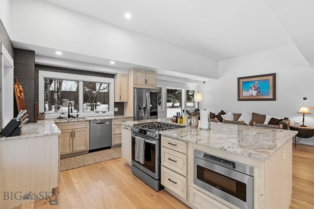 9 Park Plaza Rd, Bozeman, MT 59715 - kitchen with light stone countertops, a sink, light wood-style floors, stainless steel appliances, and a kitchen island