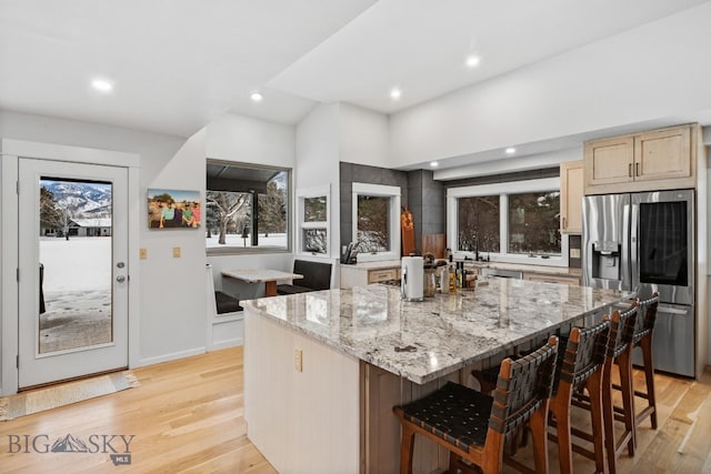 9 Park Plaza Rd, Bozeman, MT 59715 - kitchen featuring stainless steel fridge with ice dispenser, a kitchen bar, a kitchen island, light wood finished floors, and light stone counters