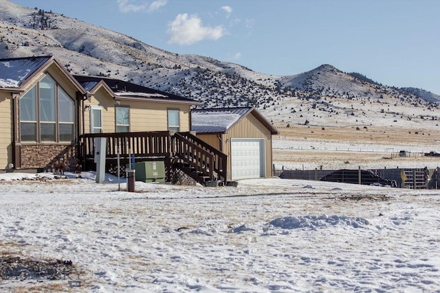 snow covered rear of property with a garage and a mountain view