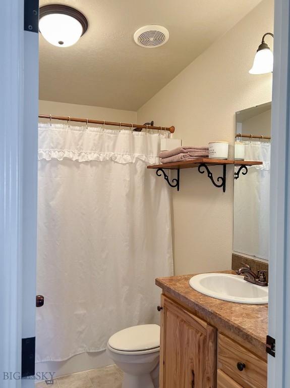 bathroom featuring tile patterned flooring, vanity, walk in shower, and toilet