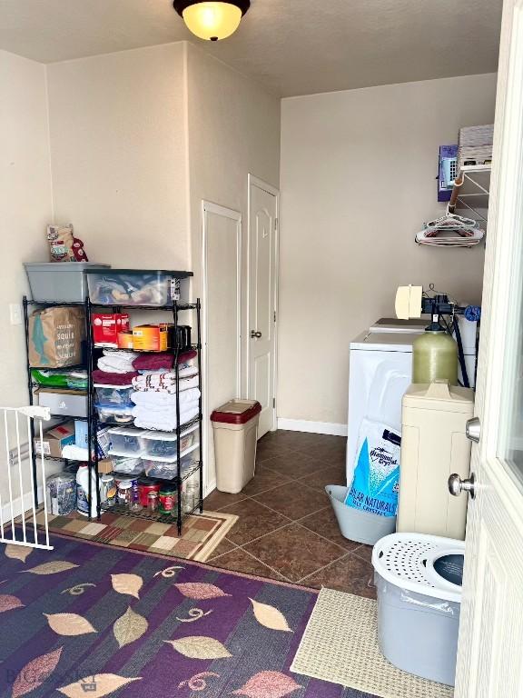 laundry area featuring washing machine and clothes dryer and dark tile patterned flooring