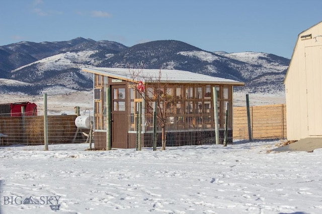 snow covered back of property featuring a mountain view