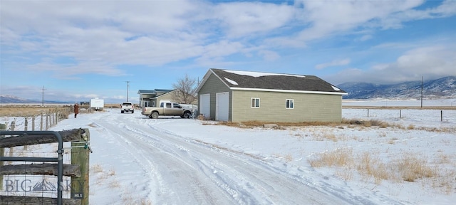 snow covered property with a garage and an outbuilding