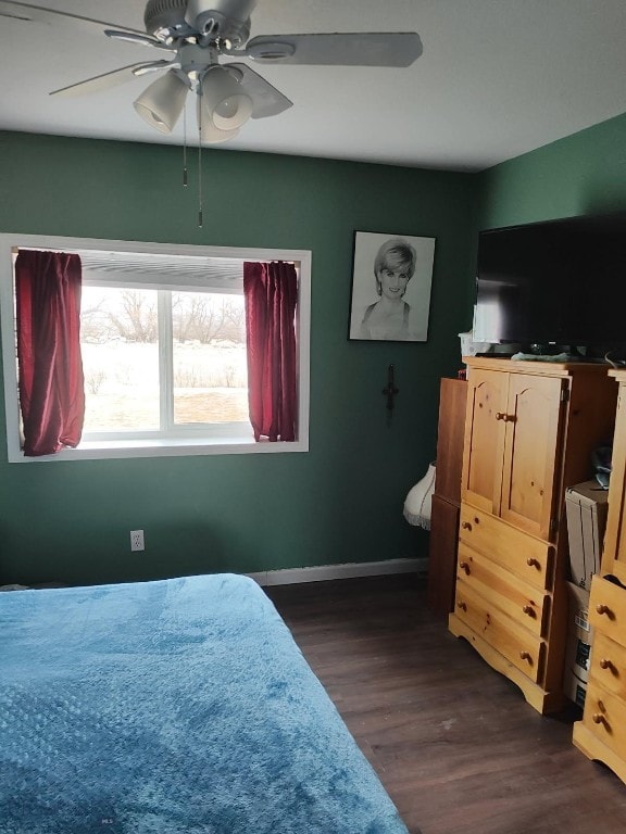 bedroom with dark wood-style floors, a ceiling fan, and baseboards