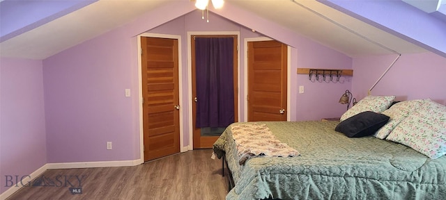 bedroom with vaulted ceiling, wood finished floors, and baseboards