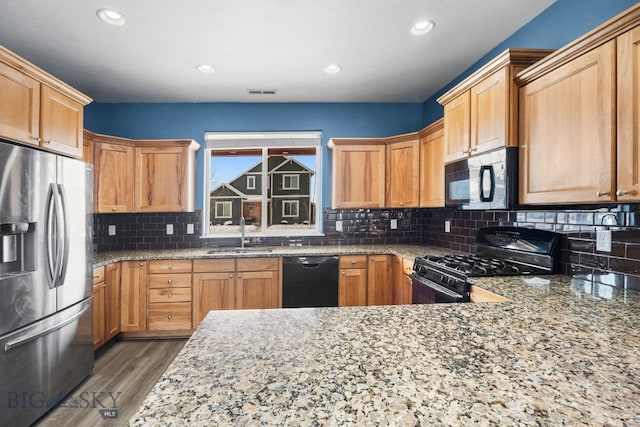 kitchen featuring tasteful backsplash, visible vents, wood finished floors, black appliances, and a sink