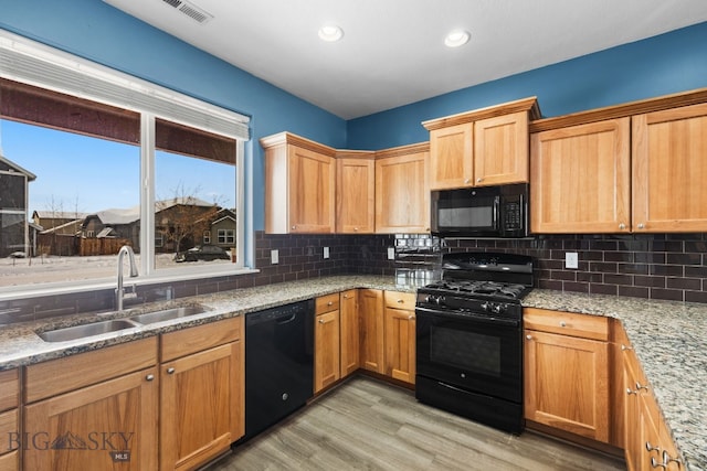 kitchen with black appliances, visible vents, backsplash, and a sink