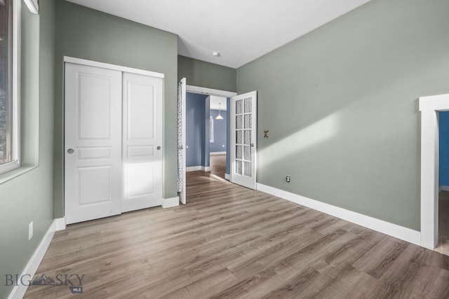 unfurnished bedroom featuring a closet, wood finished floors, and baseboards