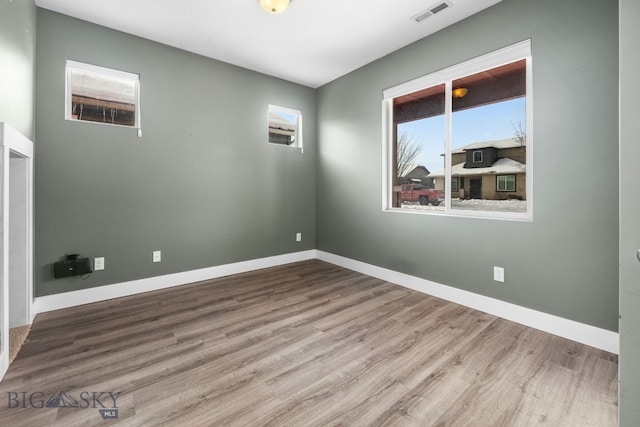 spare room featuring visible vents, baseboards, and wood finished floors