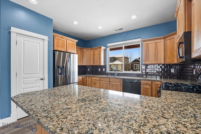 kitchen featuring tasteful backsplash, visible vents, a sink, a peninsula, and black appliances