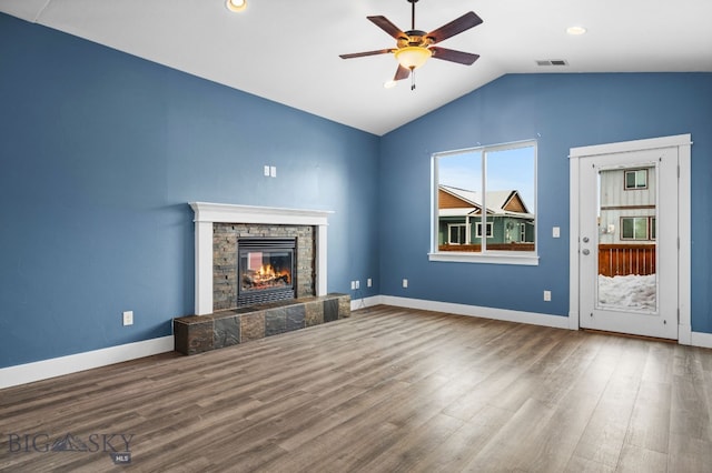 unfurnished living room featuring baseboards, ceiling fan, wood finished floors, vaulted ceiling, and a stone fireplace