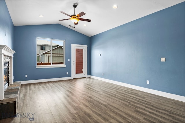 unfurnished living room with lofted ceiling, visible vents, a ceiling fan, a glass covered fireplace, and wood finished floors