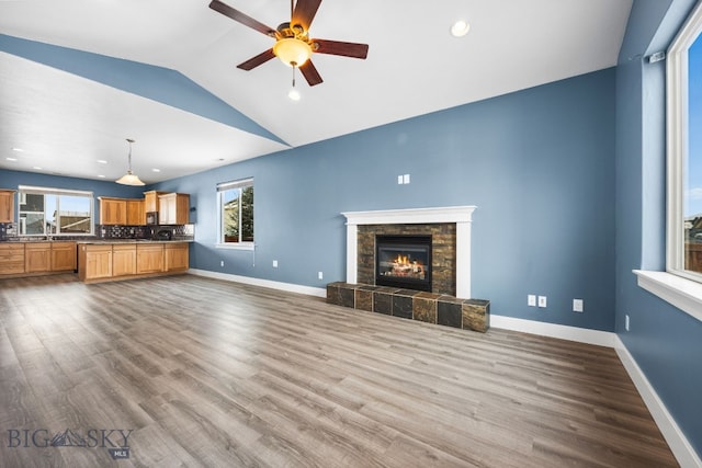 unfurnished living room featuring dark wood-style flooring, a tiled fireplace, and baseboards