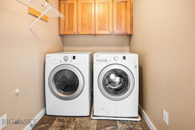 washroom with cabinet space, washing machine and dryer, baseboards, and stone finish flooring