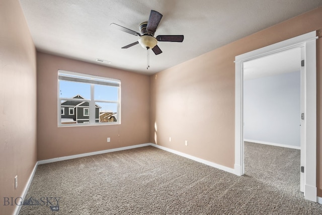 carpeted empty room featuring a ceiling fan, visible vents, and baseboards