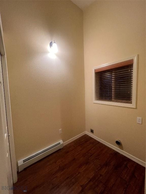 empty room with baseboard heating and dark hardwood / wood-style floors