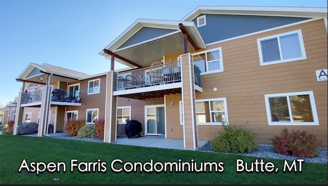 rear view of property featuring a balcony and a yard