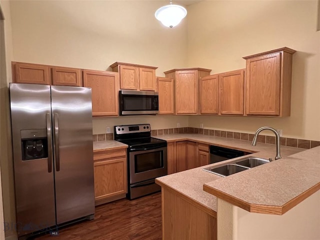 kitchen featuring kitchen peninsula, stainless steel appliances, dark hardwood / wood-style floors, light brown cabinets, and sink