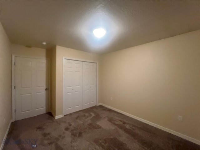 unfurnished bedroom featuring a closet and dark colored carpet