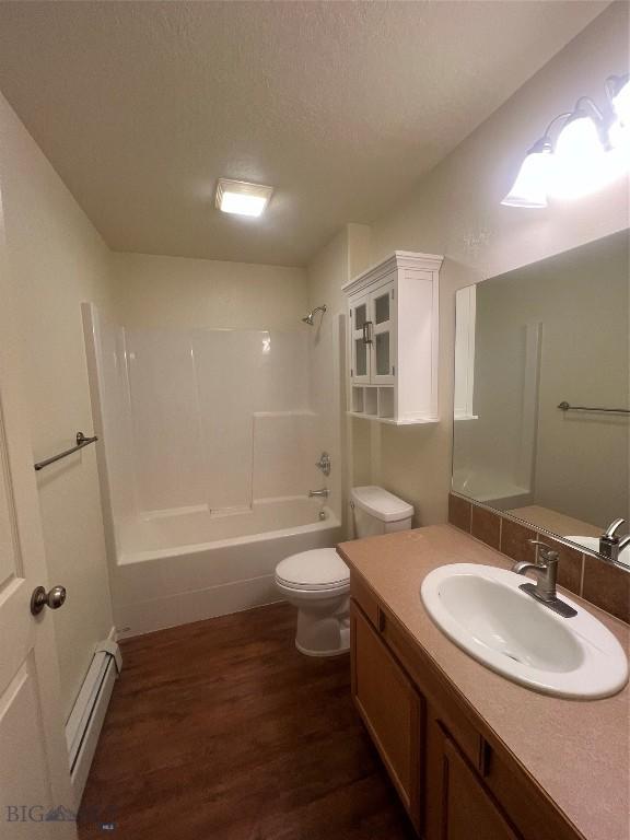 full bathroom with a textured ceiling, wood-type flooring, a baseboard heating unit, shower / washtub combination, and toilet