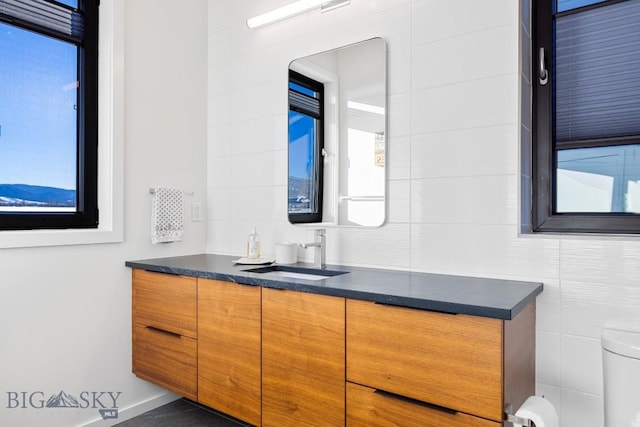 bathroom featuring toilet, vanity, and tile walls