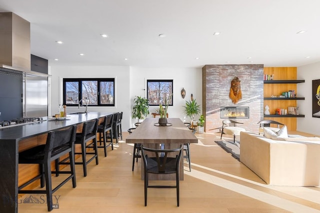 dining room with a large fireplace, sink, and light hardwood / wood-style flooring