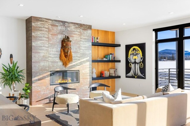 living room featuring a mountain view, light hardwood / wood-style flooring, and a tiled fireplace