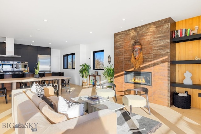 living room featuring a fireplace, wooden walls, and sink