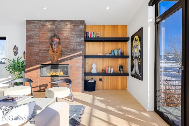 living room with a healthy amount of sunlight, a large fireplace, and light hardwood / wood-style flooring