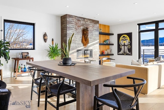 dining room with light wood-type flooring, a mountain view, and a tiled fireplace