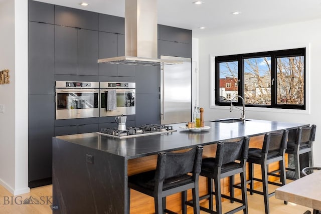 kitchen featuring a kitchen bar, sink, appliances with stainless steel finishes, and an island with sink