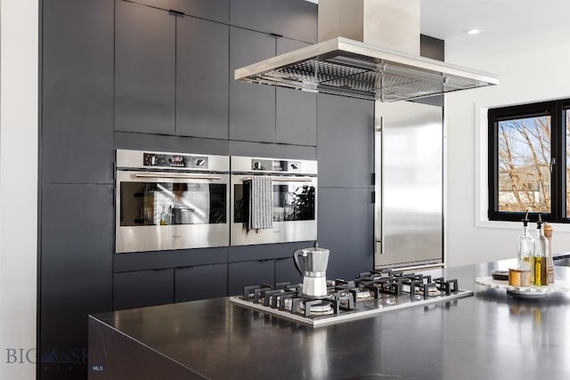 kitchen with island exhaust hood and stainless steel gas stovetop