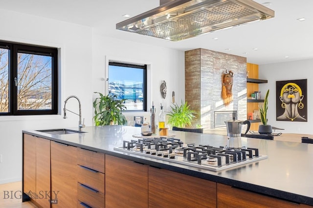 kitchen with stainless steel gas stovetop, exhaust hood, and sink