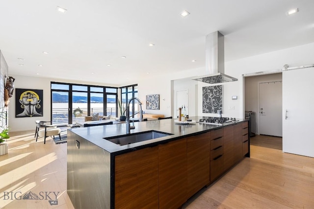 kitchen with island exhaust hood, a spacious island, stainless steel gas cooktop, expansive windows, and sink