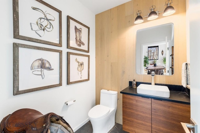 bathroom with toilet, vanity, and wooden walls