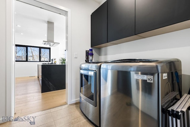 clothes washing area featuring cabinets, light tile patterned floors, separate washer and dryer, and sink