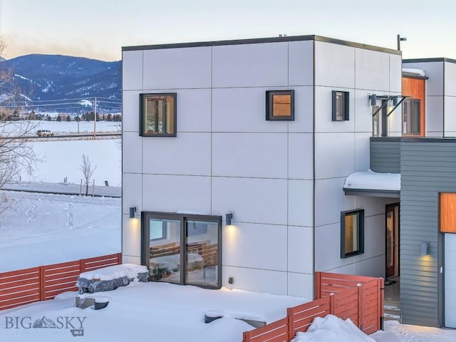 snow covered back of property with a mountain view